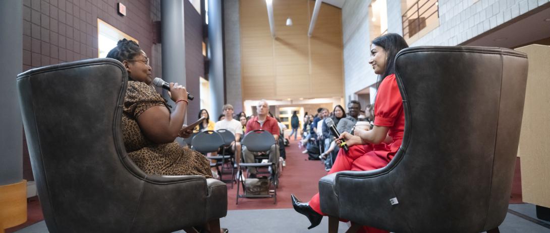 Two women sit in arm chairs talking to an audience in Zoellner Arts Center.